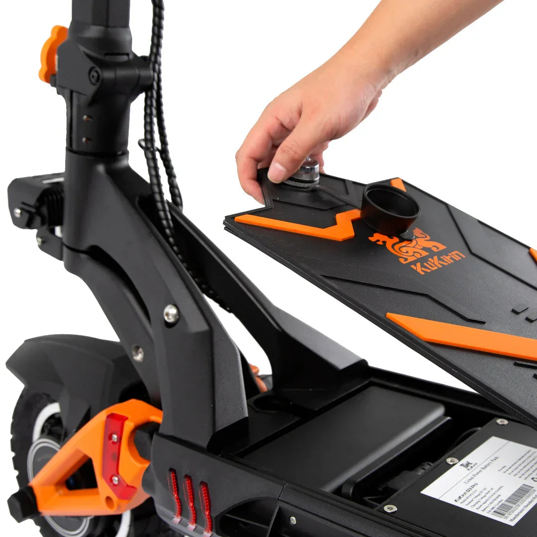 Hand accessing battery compartment on black and orange electric scooter with Xukim branding