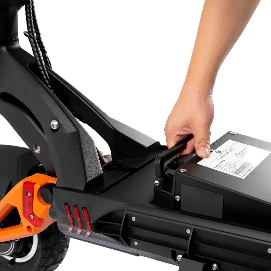 Hand removing battery from black and orange electric scooter with red taillights