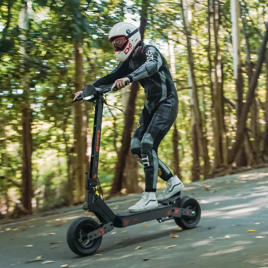 Rider in full gear cruising on a black electric scooter through a sunlit forest path